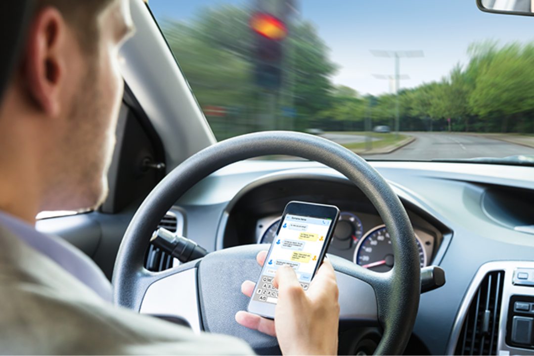 homme envoyant un sms au volant