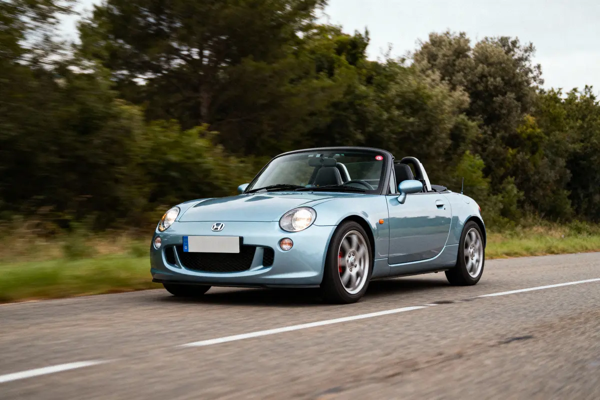 Voiture cabriolet argentée roulant sur une route bordée d'arbres, vue en mouvement.