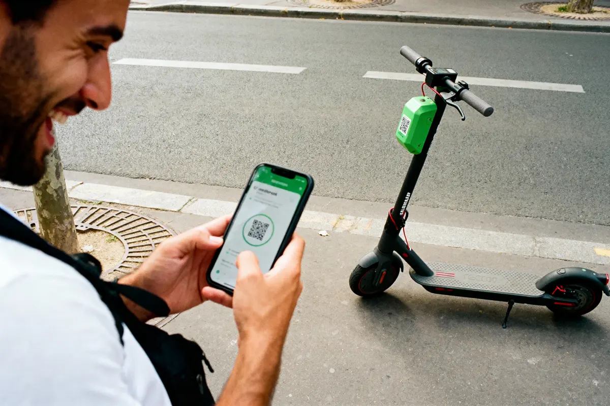 Homme scanne QR code trottinette électrique avec smartphone, rue urbaine en arrière-plan.