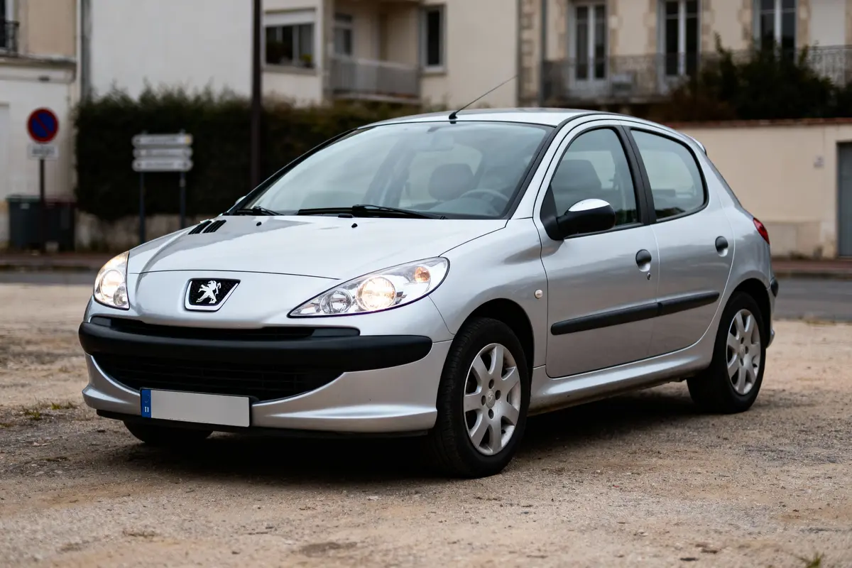 Voiture grise Peugeot garée sur un parking en extérieur, devant des bâtiments.