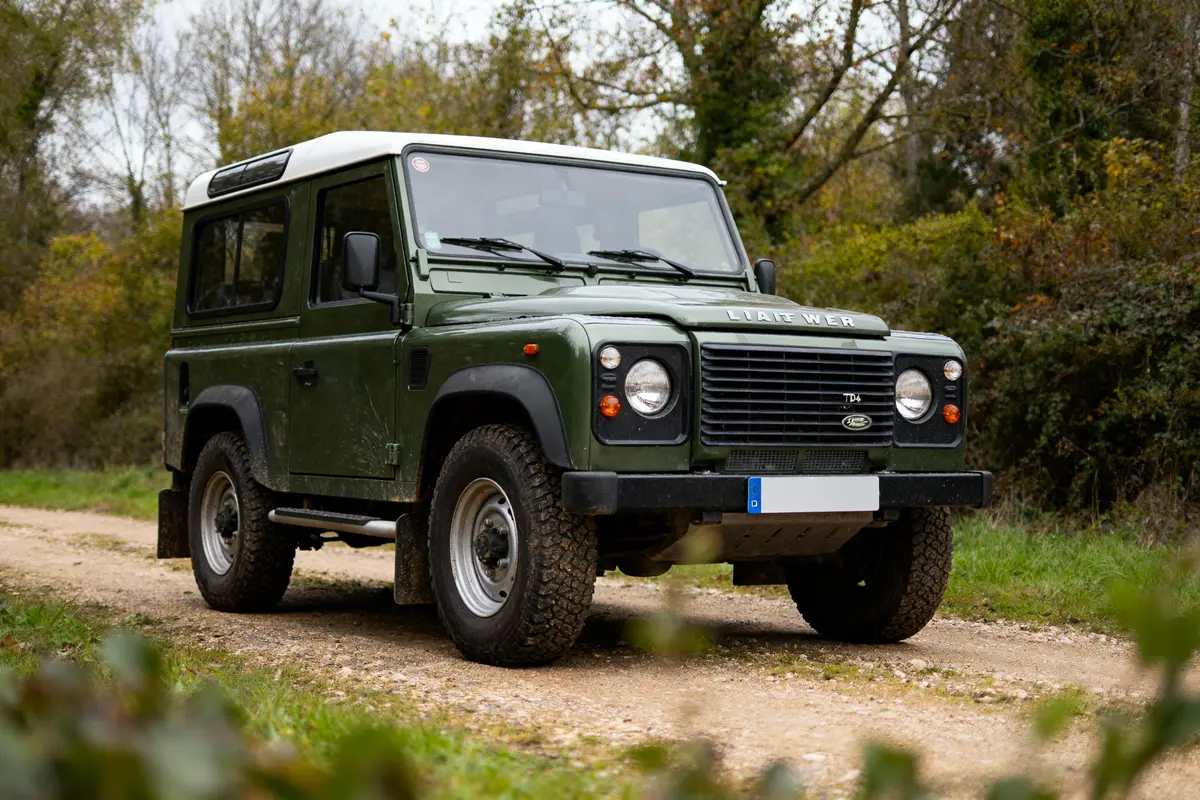 4x4 vert garé sur chemin de terre entouré de végétation automnale. Véhicule tout-terrain robuste et classique.