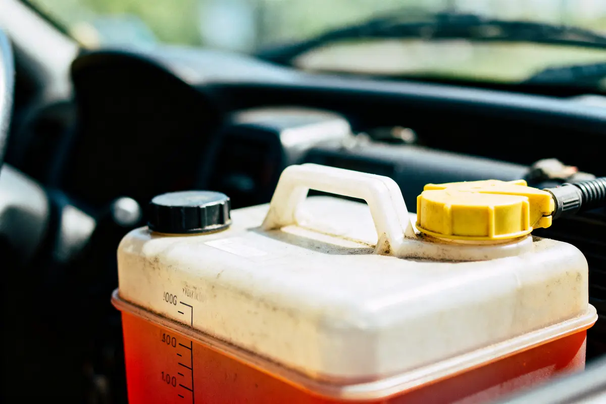 Gros plan d'un récipient en plastique avec bouchon noir et jaune, à l'intérieur d'une voiture.