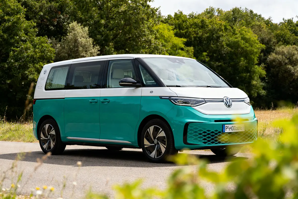Fourgonnette électrique ID Buzz California stationnée sur une route bordée d'arbres verts
