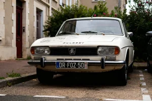 Voiture ancienne stationnée, avant blanc de la Peugeot 506 visible sur une rue résidentielle