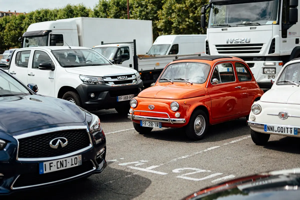 Plusieurs voitures, dont une marque de voiture en I, sur un parking urbain.
