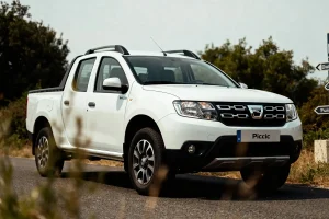 Pickup truck blanc sur route, entouré de verdure, avec plaques d'immatriculation "Piccic" visible à l'avant.