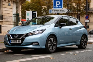 Voiture électrique Nissan Leaf bleue stationnée près d'une borne de recharge urbaine.