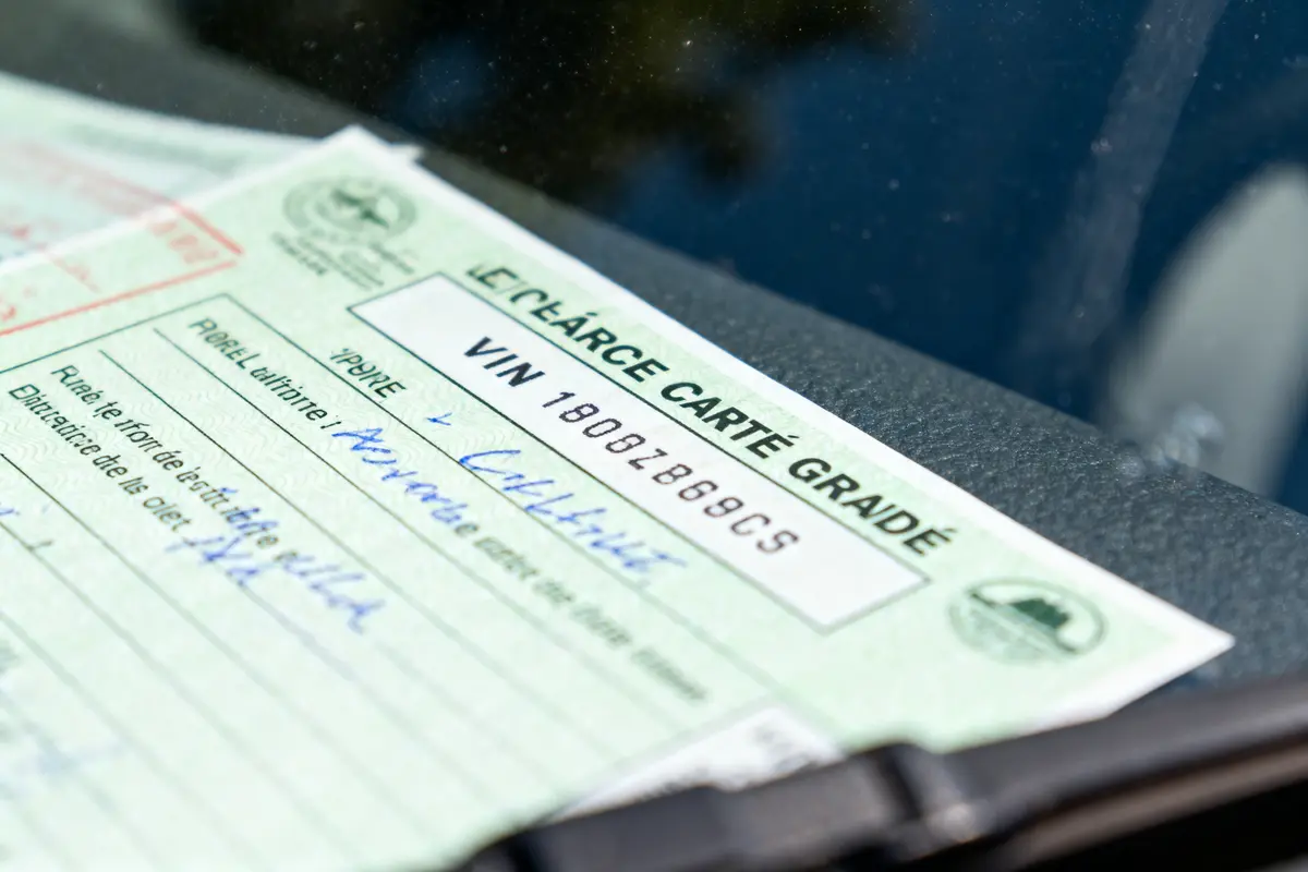 Carte verte d'assurance auto visible derrière le pare-brise d'une voiture, avec détails manuscrits.