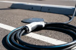 Câble de recharge électrique 7kW sur un parking asphalté, près d'une station de chargement.