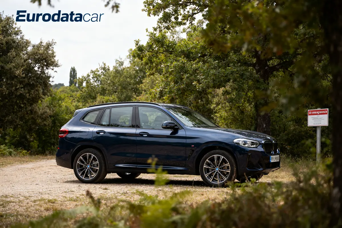 SUV bleu stationné sur un chemin terreux entouré d'arbres, logo Eurodatacar visible en haut à gauche.