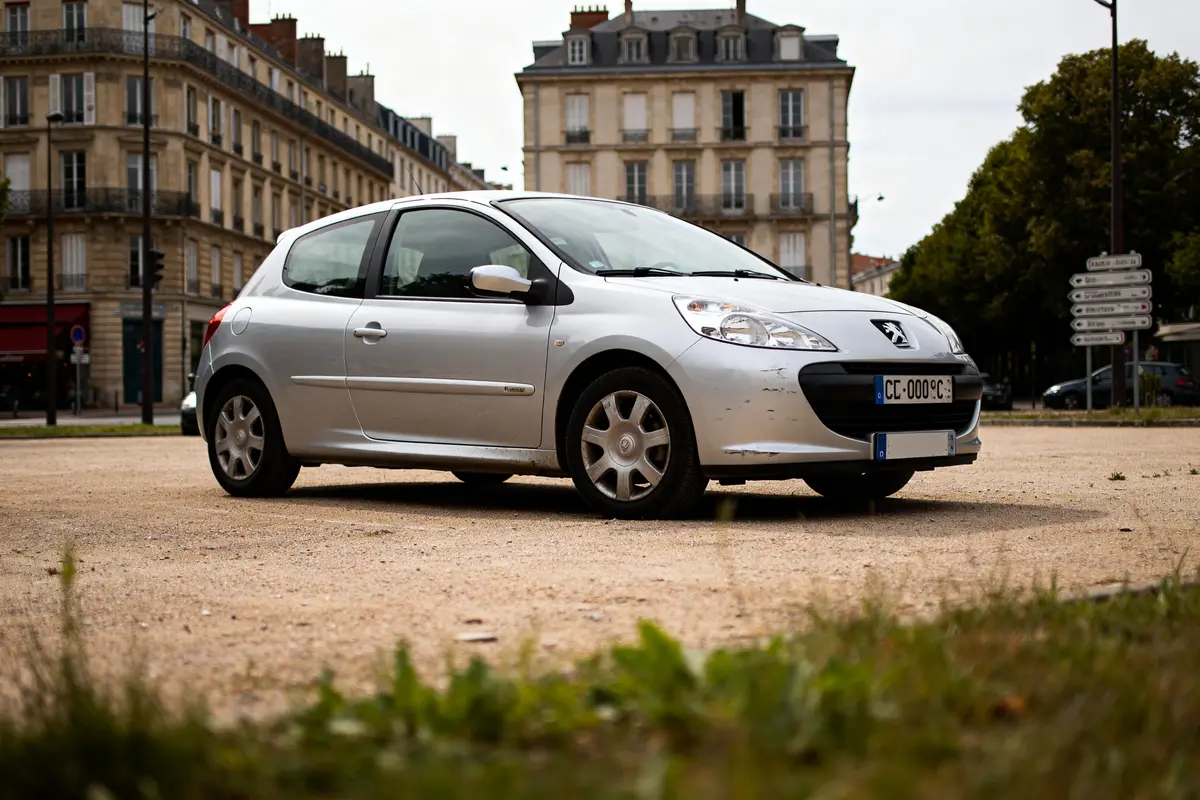 Voiture argentée devant immeubles, exemple de voiture à 5000 euros abordable en ville