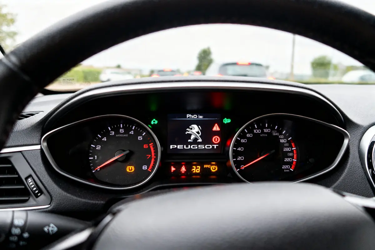 Tableau de bord d'une Peugeot 208 avec voyants allumés et logo central affiché.