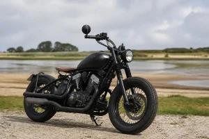 Moto Bobber 125 noire stationnée près d'un lac sur fond de paysage naturel