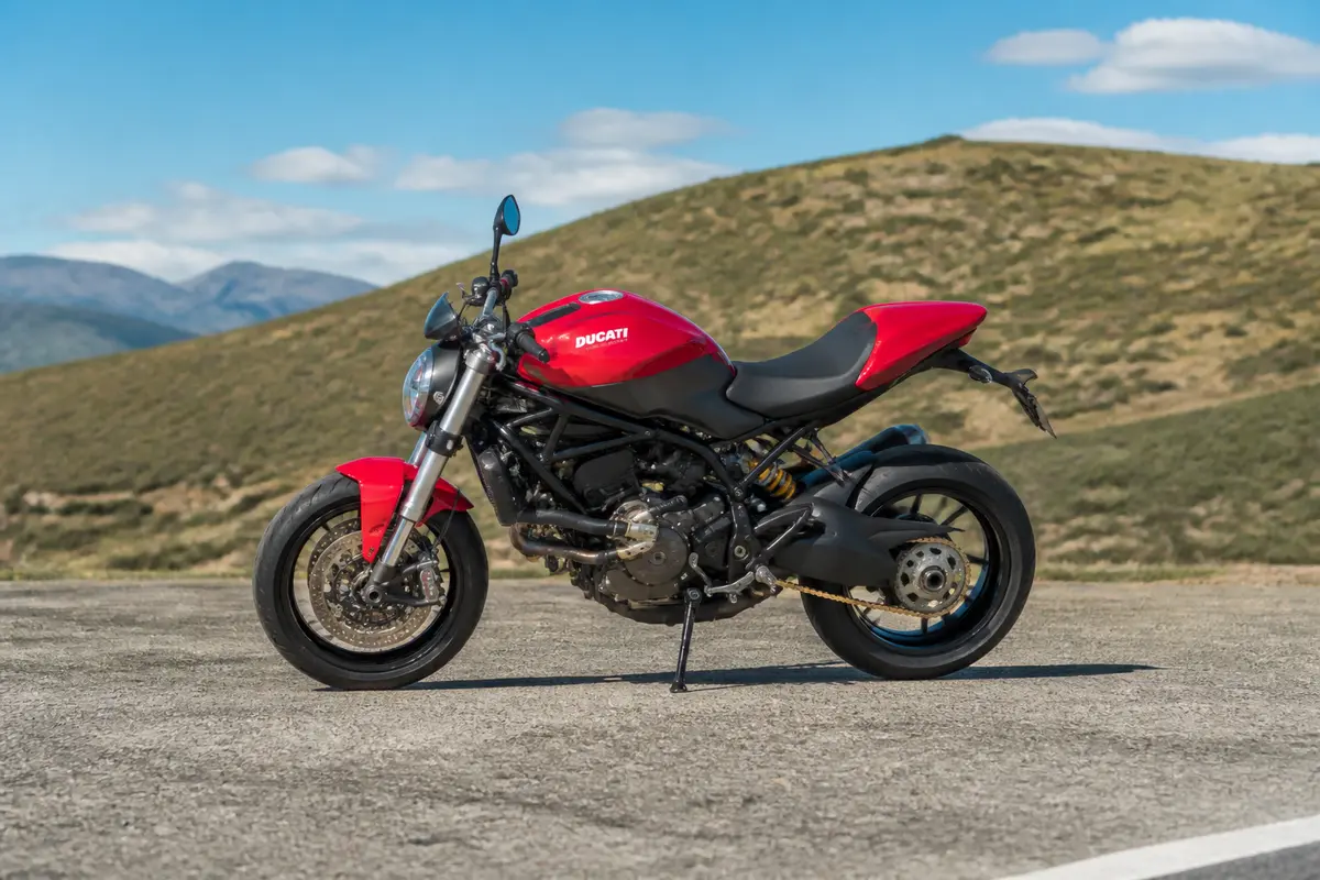 Moto rouge Ducati garée sur route devant paysage montagneux, marque de moto italienne emblématique